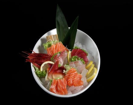 round plate of sushi and sashimi on black background