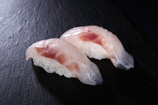 two sushi on flat slate, black background