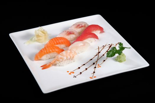 various sushi with wasabi on white plate, black background