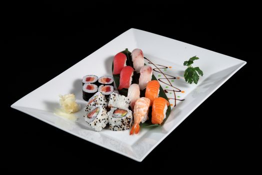 various sushi and sashimi with wasabi on white plate, black background