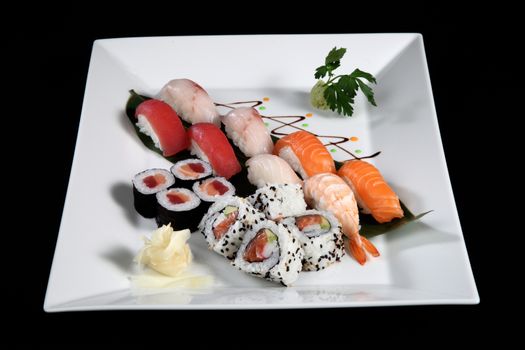 various sushi and sashimi with wasabi on white plate, black background