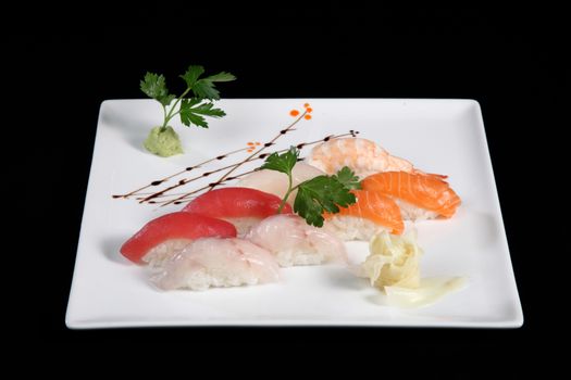 various sushi with wasabi on white plate, black background