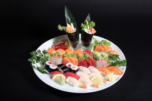 round plate of sashimi and sushi with mixed vegetables and ice