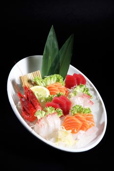 round plate of sashimi and sushi with mixed vegetables and ice