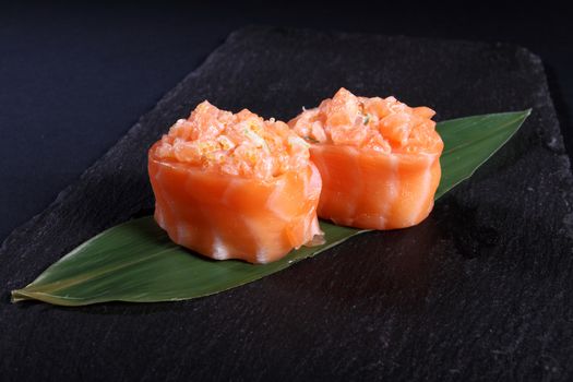 stew salmon on green leaf, black background