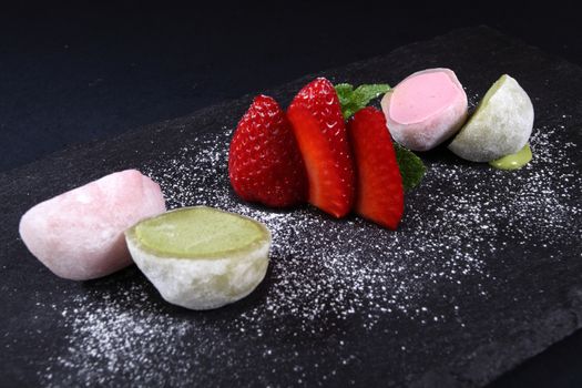 half scoops of ice cream with strawberries on black background