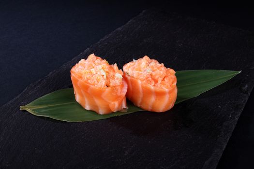 stew salmon on green leaf, black background