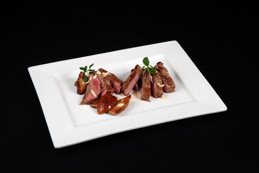 beef with mushrooms in white plate on a black background