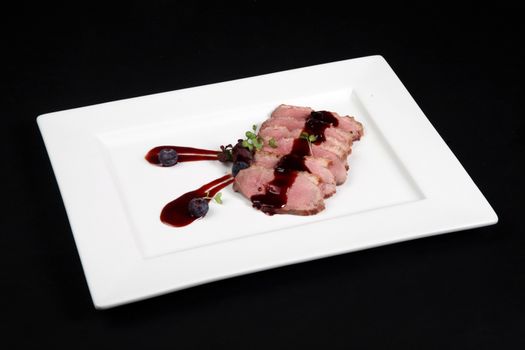 duck meat with cranberry cream in white plate on a black background