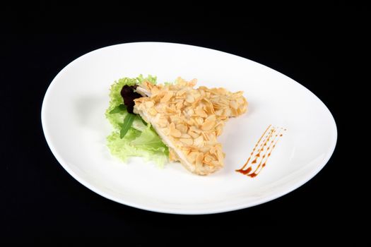 chicken with almonds in the oval plate on a black b