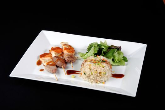 menu of kebabs with rice and vegetables in white dish, on black background