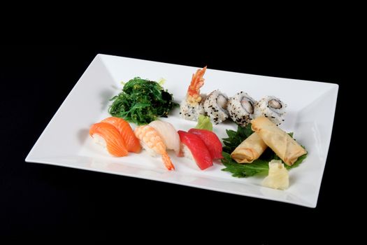 menu of sushi and roll fish with vegetables on white plate, on black background