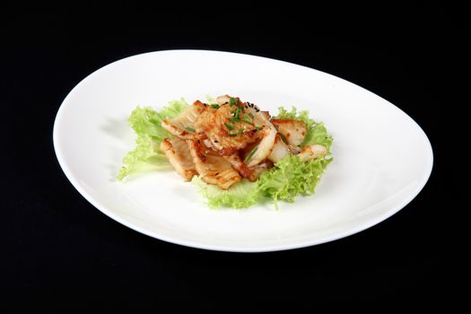 grilled calamari in white plate on a black background