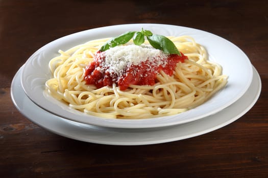 Italian dish of spaghetti with tomato and basil on a wooden table