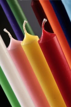 group of colorful cylindrical candles on a black background