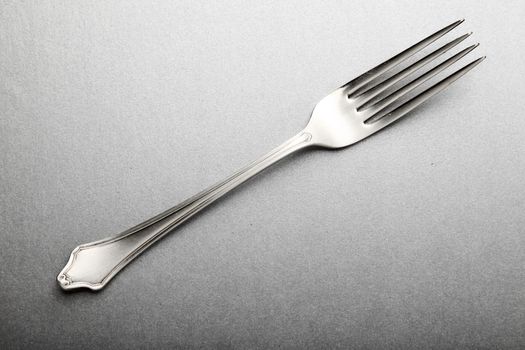 elegant steel fork engraved on the handle, on silver background