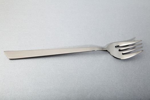elegant steel fork for fish, on a silver background