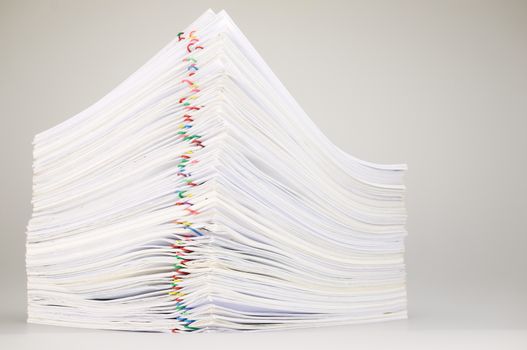 Pile overload paperwork of receipt and report with colorful paperclip on white table.