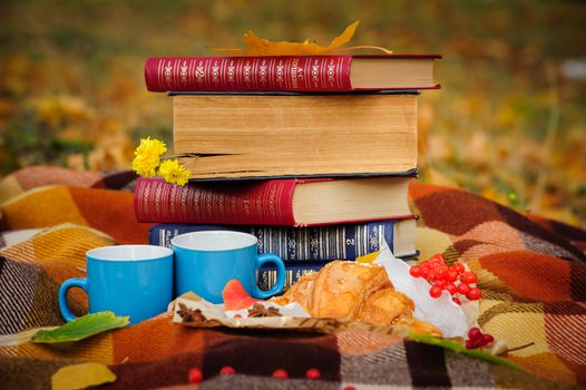 Romantic autumn still life with books, plaid, croissant, coffee cups and leaves