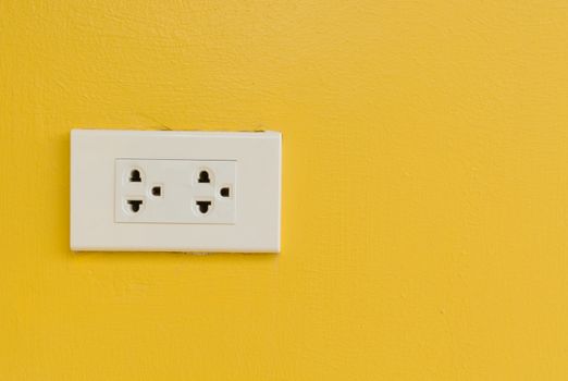 White electric plug on yellow wall. Bright background