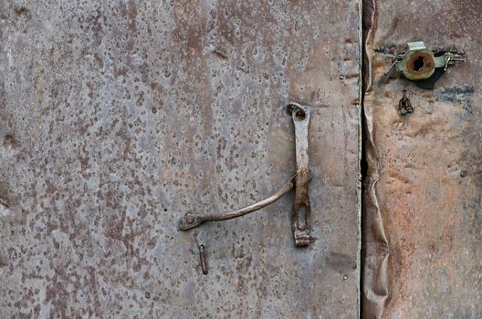 Part of the rusty iron door, with a latch and a broken lock