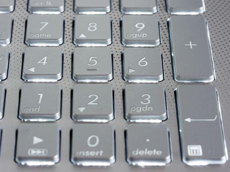 Number keys on silver keyboard of laptop, close up, horizontal image. Shallow DOF