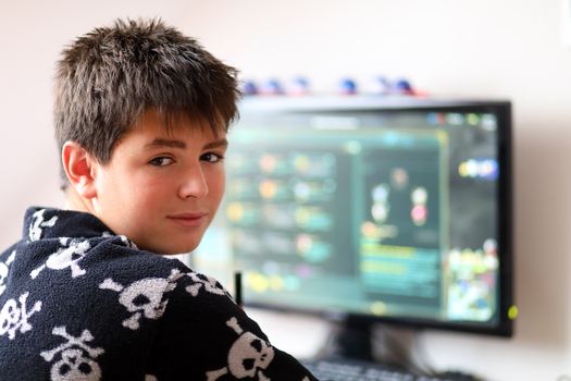 Teenager boy using computer at home with play online game in his child room
