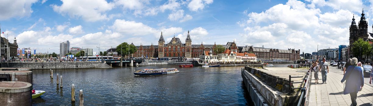 AMSTERDAM - JULY 10, 2016: Big panoramic of Central Station and canal, July 10, 2016 in Amsterdam. Central Station is the central railway station of Amsterdam and is used by 250,000 passengers a day.