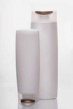 White bottles for liquids and shampoo in the bathroom, on a white background. Milk white color gives you a feeling of cleanliness and comfort.                               