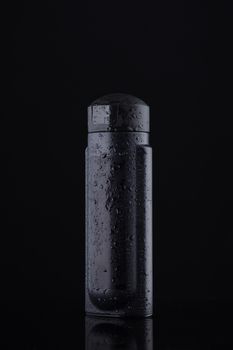 Black capacity for liquids and shampoo on a black background. The black color is a symbol of purity and order in a simple style.