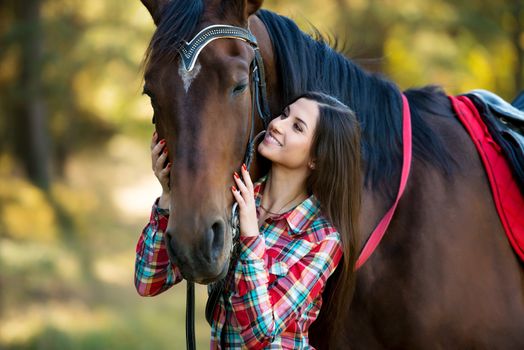 beautiful long hair young woman posing with a horse outdoor