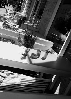 European Elegant Summer Sidewalk Cafe with Table Decoration and Striped Cushions with Morning Shadows Outdoors. Black and White Styled