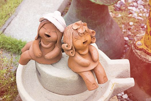 Earthenware or ceramics kid doll smile/laugh and sitting in garden. happy moment action.