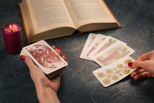 Witch using esoteric object for healing and fortune-telling; candle,Tarots and book ,vintage style.