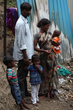 A poor Indian family of father mother and three children standing at the construction site they work at.