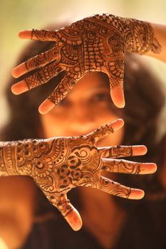 The hands of an Indian bride beautifully covered with mehendi/henna as a traditional ritual on the wedding eve.