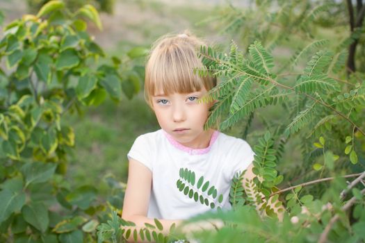 Portrait of the girl in the green bushes, close-up