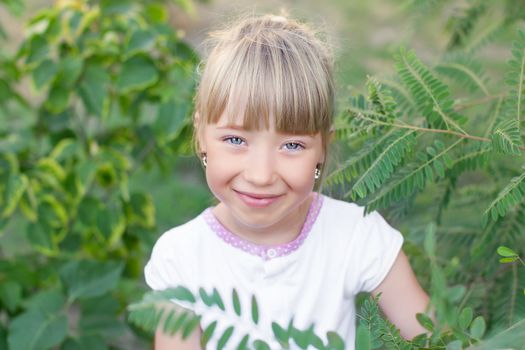 Portrait of the girl in the green bushes, close-up