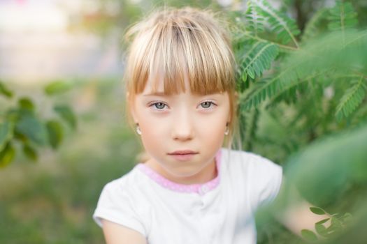 Portrait of the girl in the green bushes, close-up