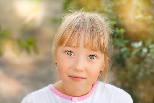 Portrait of the girl in the green bushes, close-up