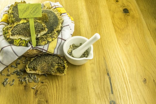 Basket with sunflower and a white mortar with crushed sunflower seeds, on a wooden table