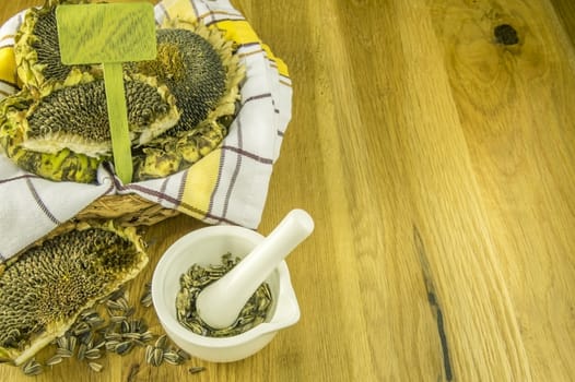 White mortar with the pestle and crushed sunflower seeds inside, in autumnal settings.