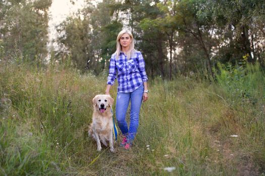Girl walking with a dog on a green meadow