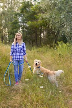 Girl walking with a dog on a green meadow