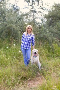 Girl walking with a dog on a green meadow