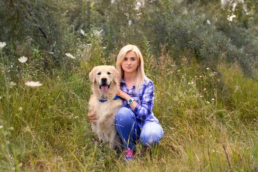 Girl walking with a dog on a green meadow