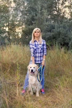 Girl walking with a dog on a green meadow