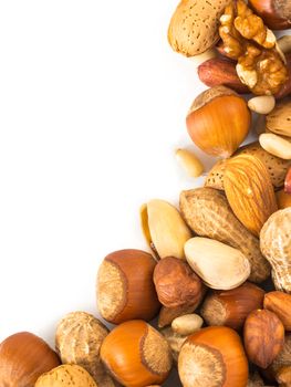 Background of mixed nuts - hazelnuts, almonds, walnuts, pistachios, peanuts, pine nuts peeled and not peeled - vertical with copy space. Isolated one edge. Top view or flat lay