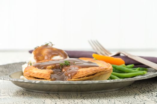 Beef and mushroom meat pie served with mashed potatoes and fresh vegetables.