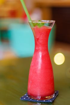 a watermelon shake with a straw and a mint leaf.